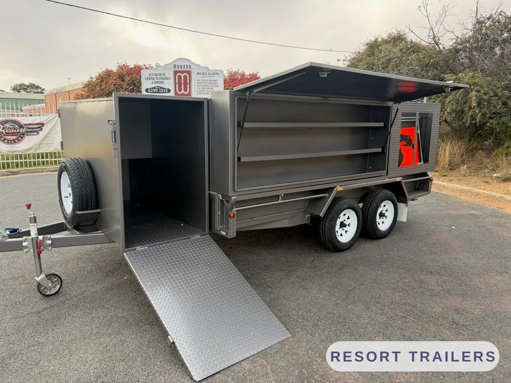 Enclosed mowing trailer with the side ramp down and the gull-wing toolbox open
